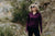 Woman wearing a purple long-sleeve shirt and sunglasses outdoors on a rocky trail.