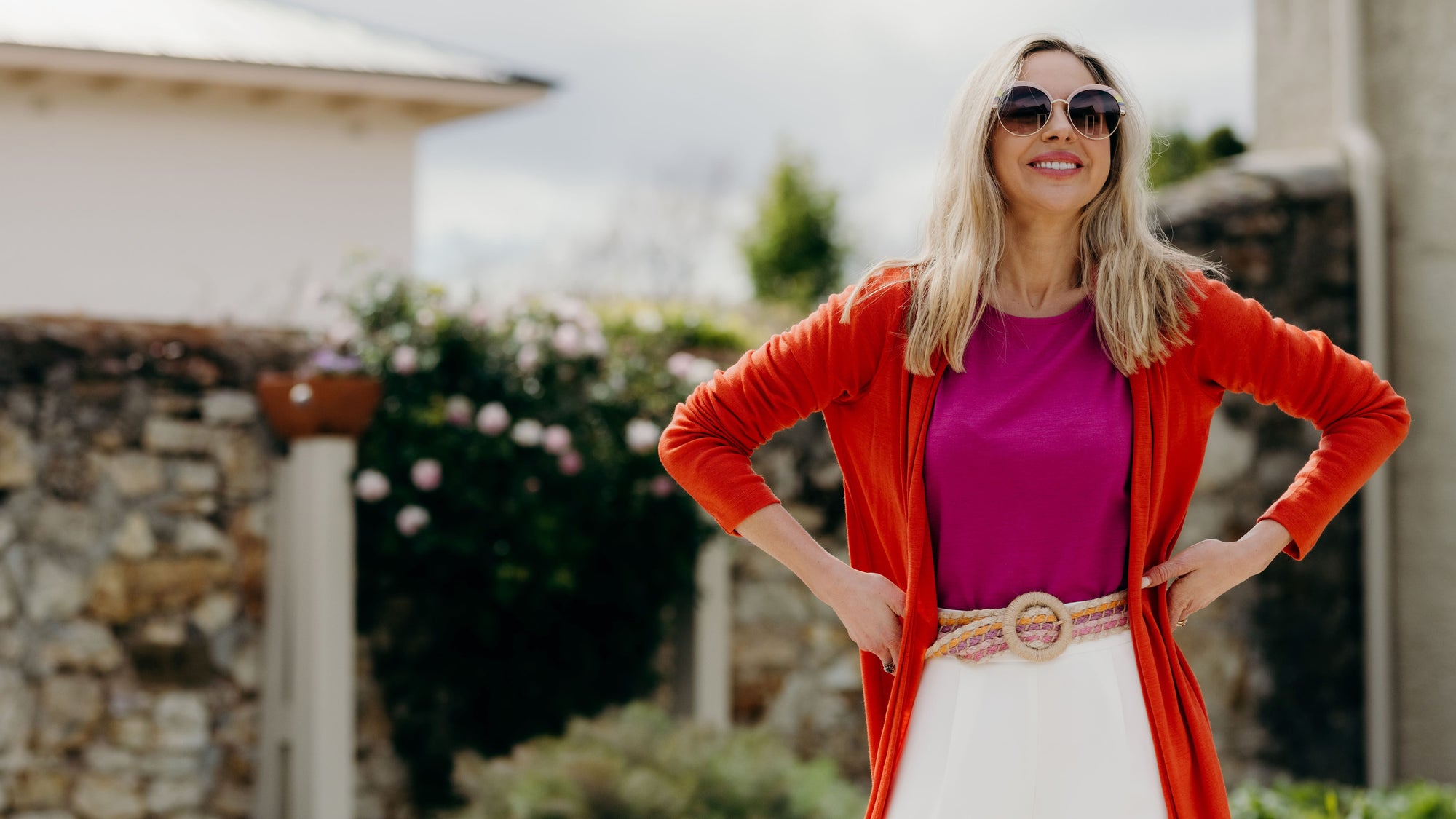 Our model wearing orange cardigan and pink top standing outside