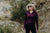 Woman wearing a purple long-sleeve shirt and sunglasses outdoors on a rocky trail.